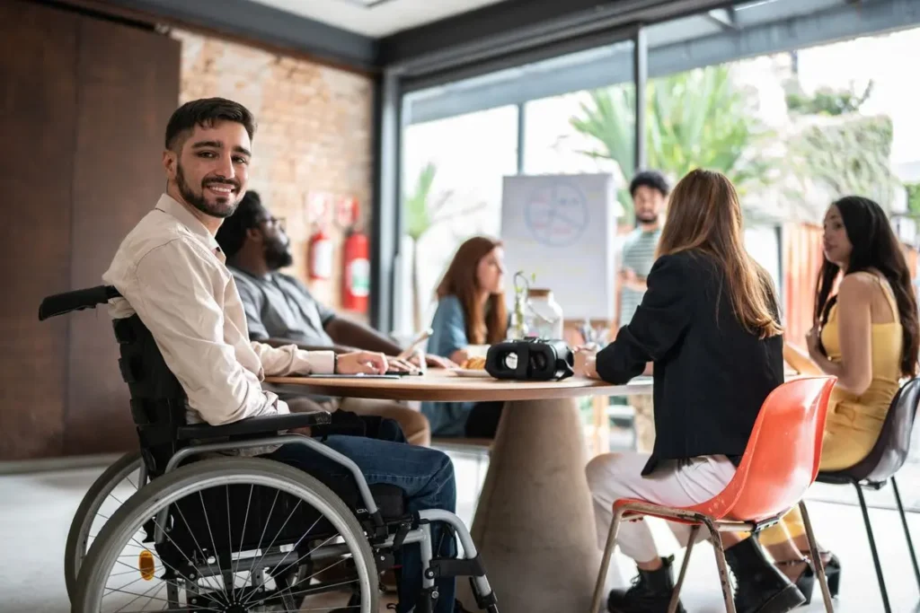 A man in a wheelchair participating in a meeting in an office