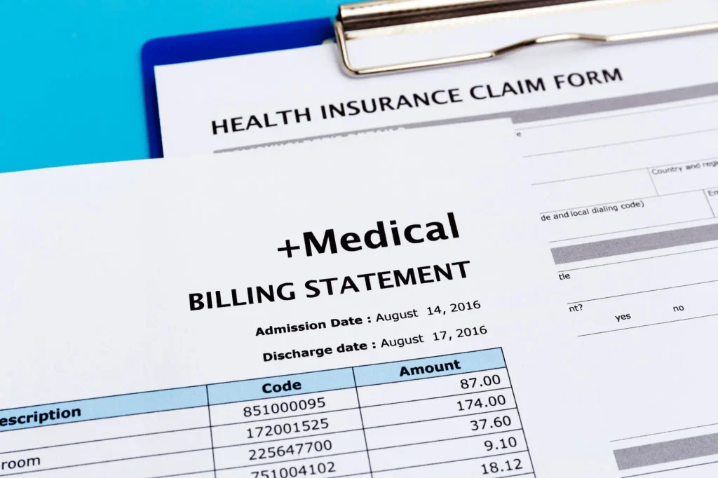 Close up of a medical billing statement and health insurance claim form showing high costs.